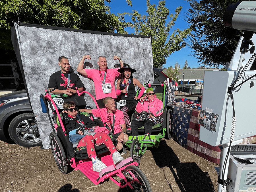 Racers, mostly in matching pink t-shirts, pose for a photo at the photo booth during our 50th Anniversary 5K in Folsom/Sacramento